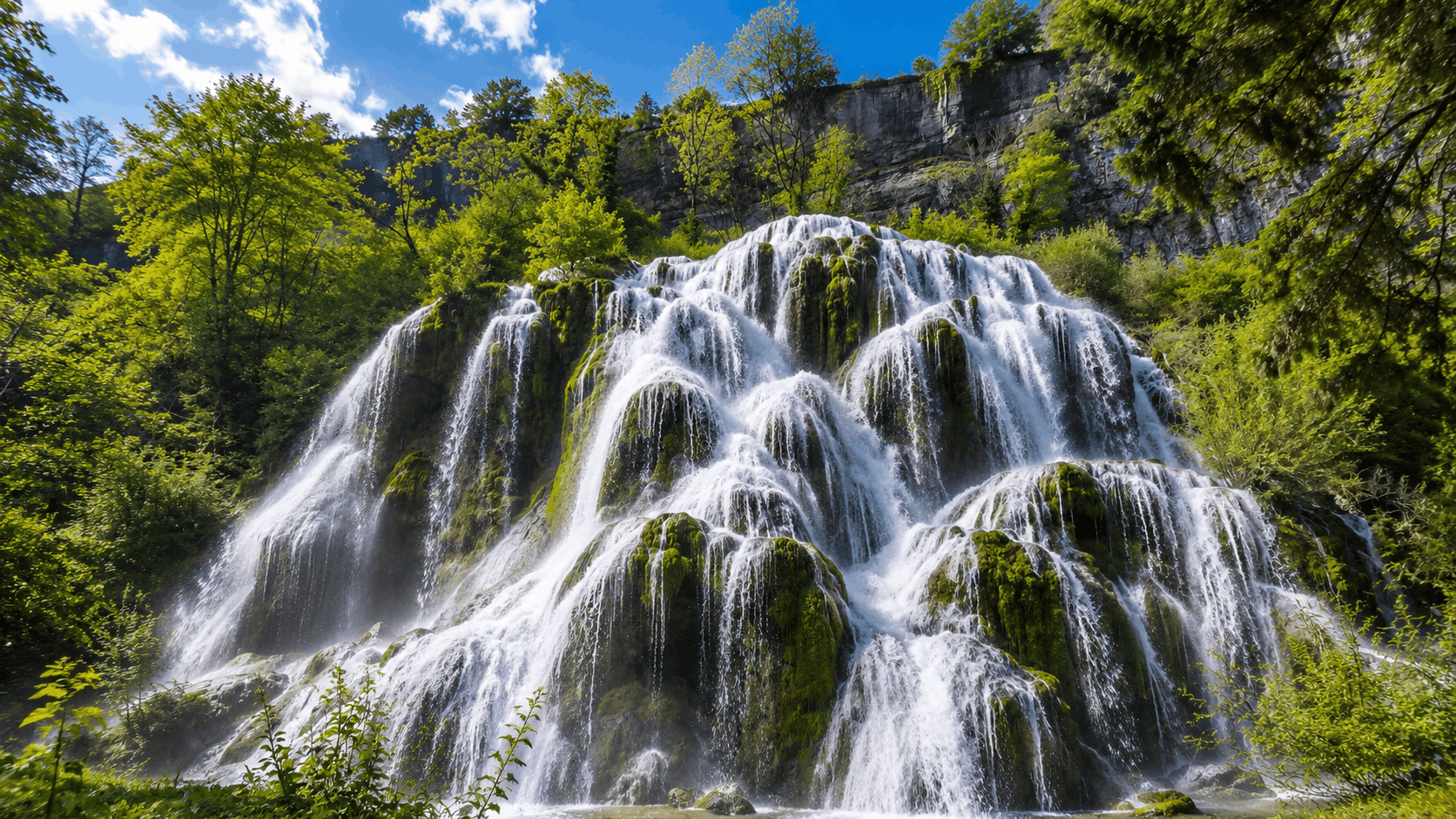 Cascade des Tufs de Baume-les-Messieurs entourée d'une végétation verdoyante dans le Jura